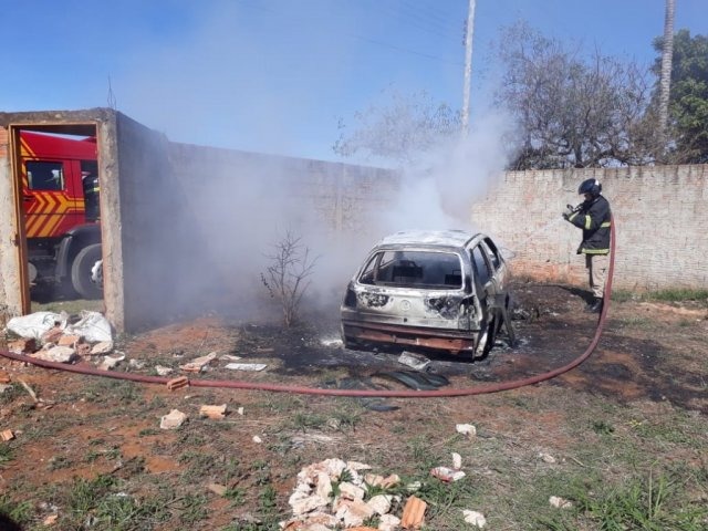 Bombeiro fazendo trabalho de rescaldo em veículo queimado em terreno (Foto: Saul Schramm)