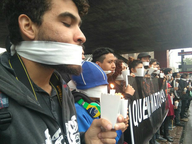 Amordaçados, manifestantes seguram velas em protesto contra chacina (Foto: Carolina Dantas/ G1)